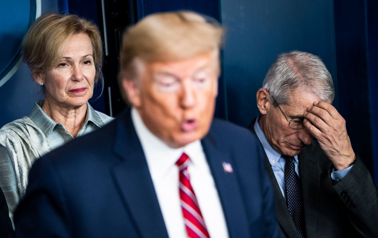 Donald Trump speaks while Dr. Anthony Fauci holds his head and looks down an Dr. Deborah Birx looks displeased
