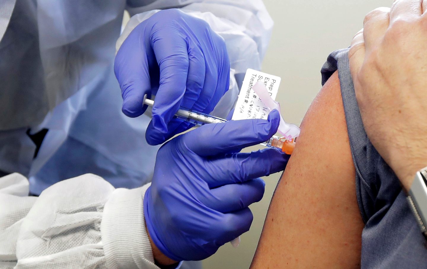A person wearing gloves injects another person with a potential Covid-19 vaccine.