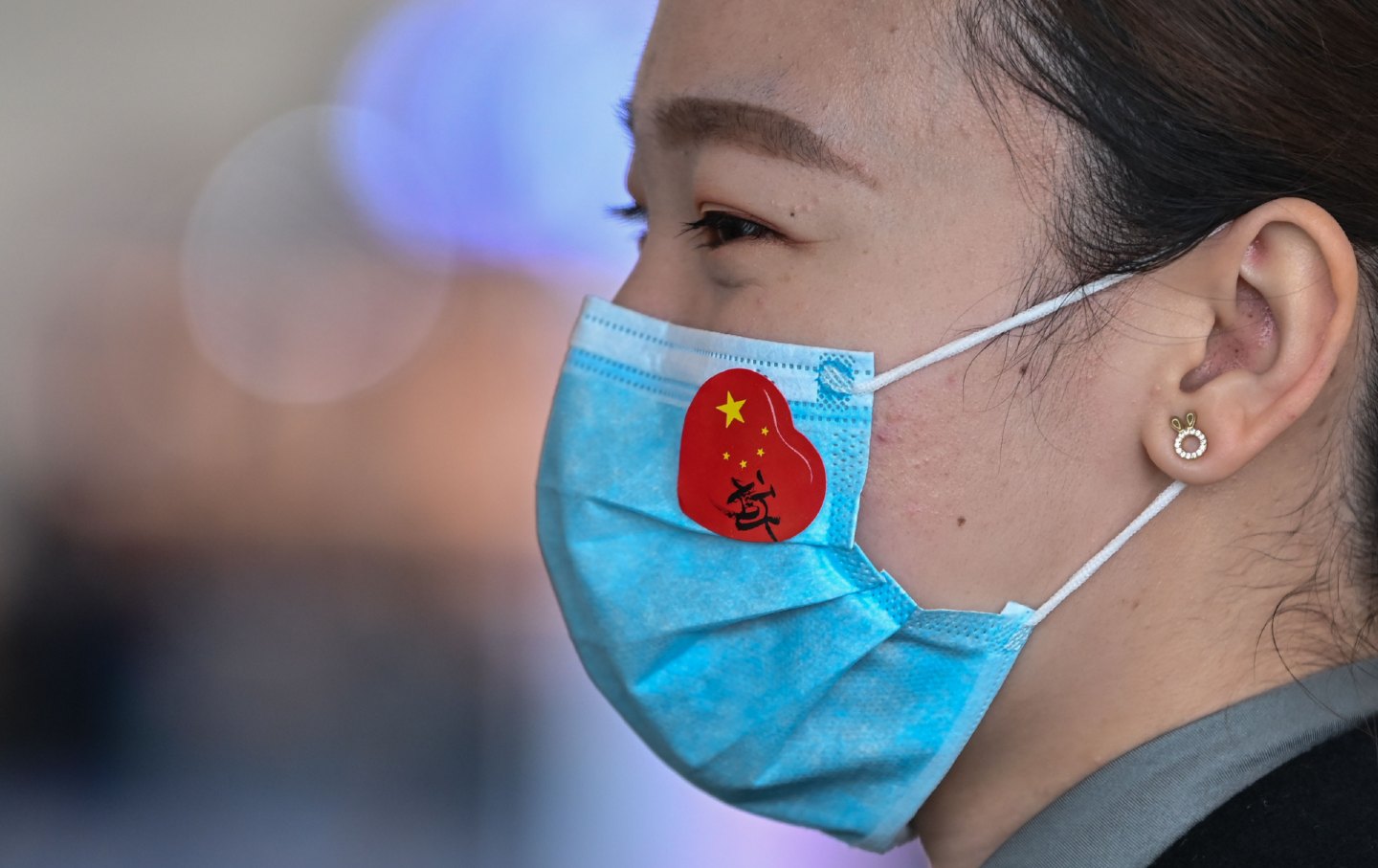 An airport worker wears a face mask with a sticker of the Chinese flag