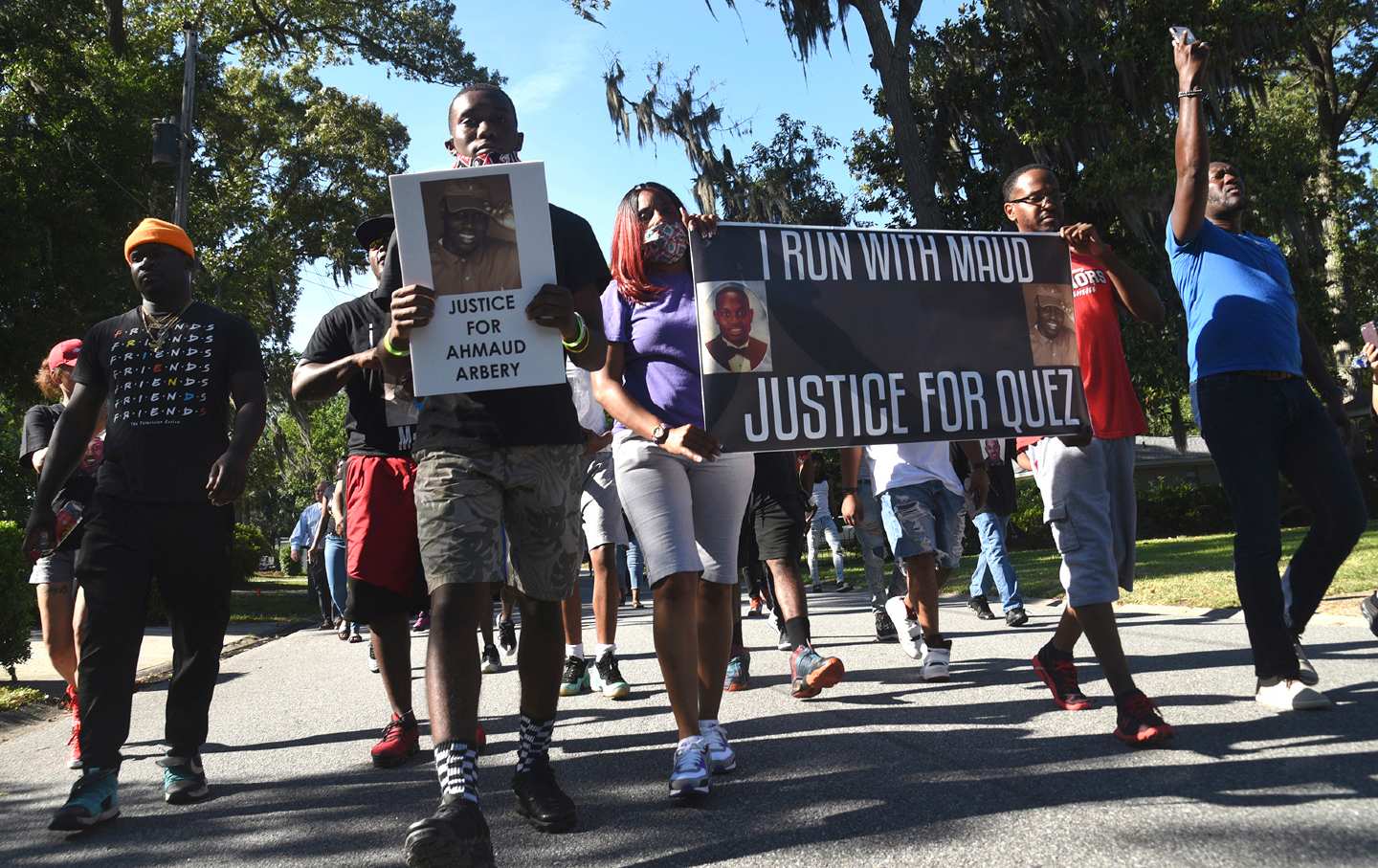 A group walks with signs and posters demanding justice for Ahmaud Arbery