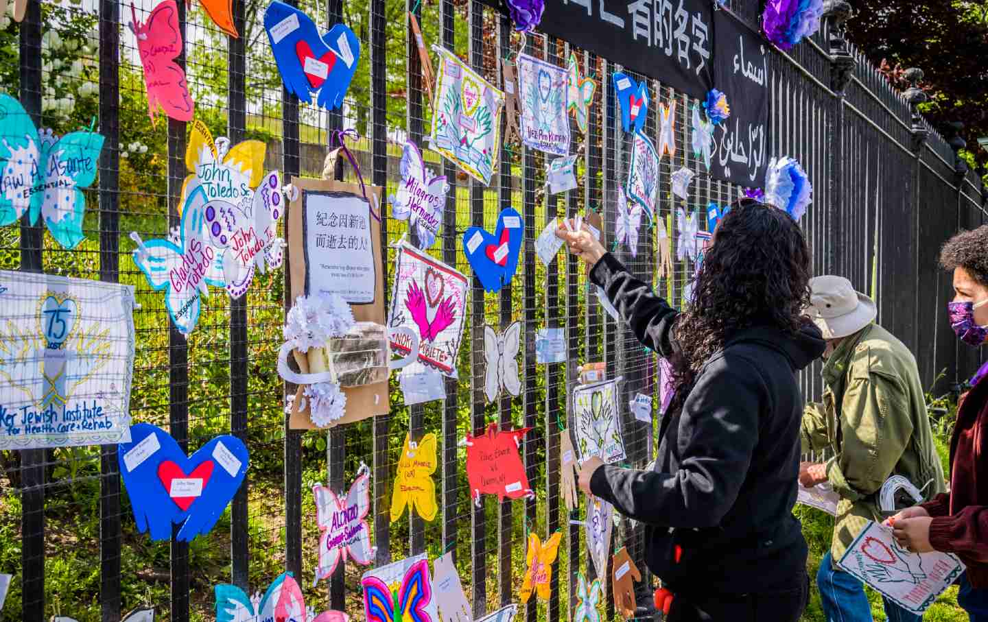 People hang signs on a fence commemorating those lost to Covid-19