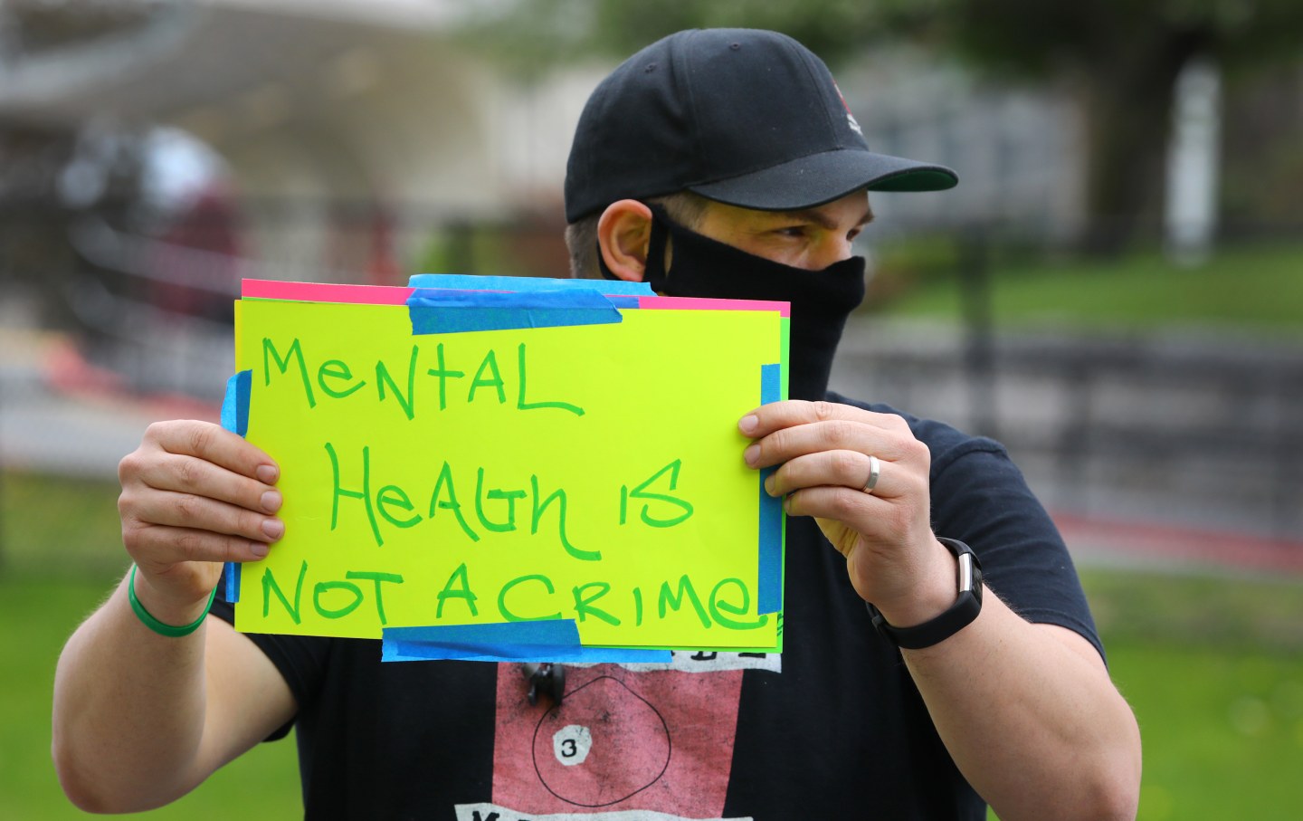A man holds a sign reading "mental health is not a crime"