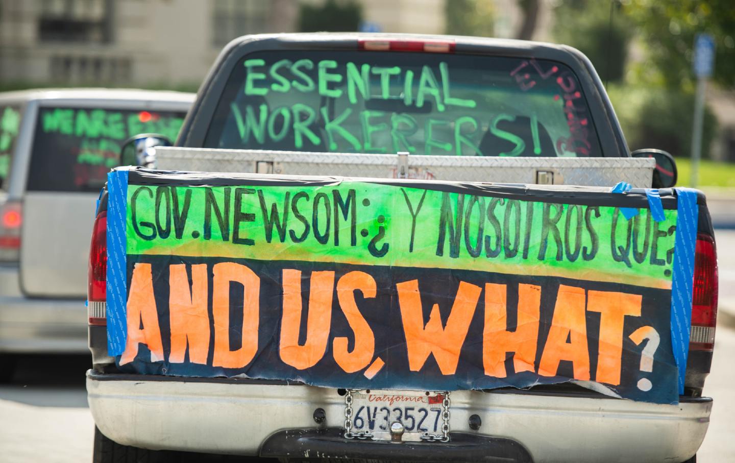 A car drives past city hall, carrying signs that read 