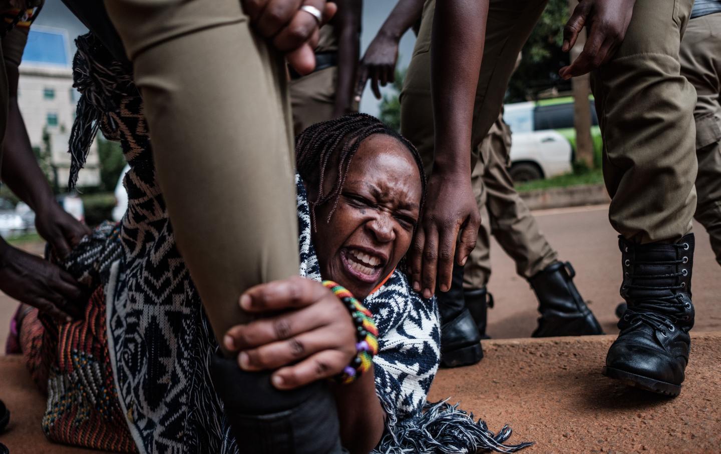 A woman holds the leg of an officer arresting her