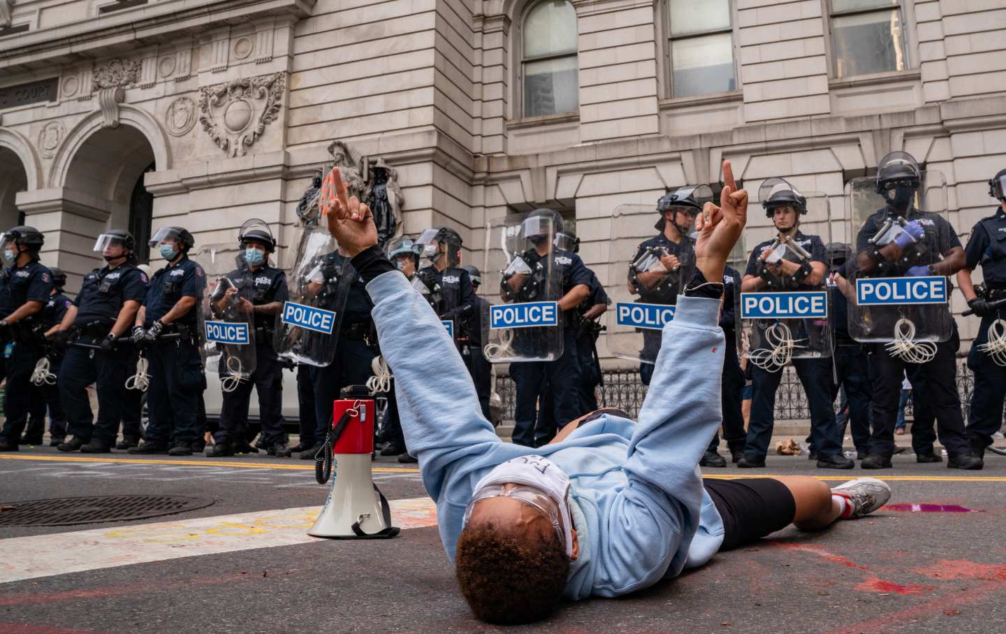 A person lies on the ground in front of a group of police officers