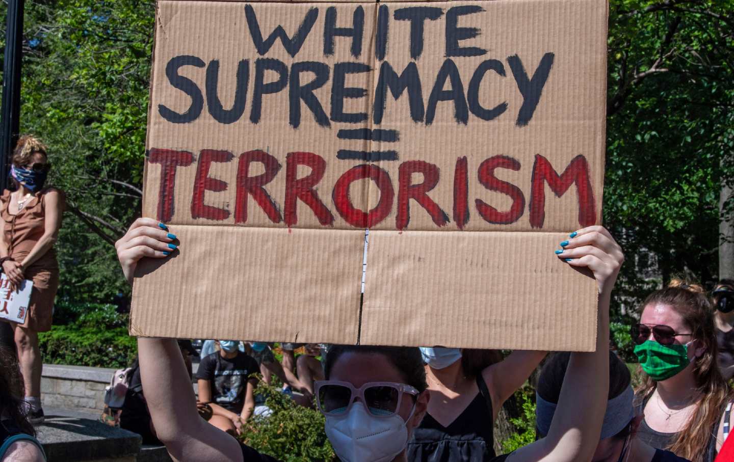 A woman holds a large piece of cardboard above her head, with the words