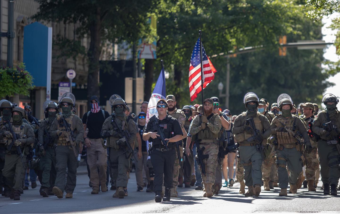 Armed gun rights protesters march down Broad Street.