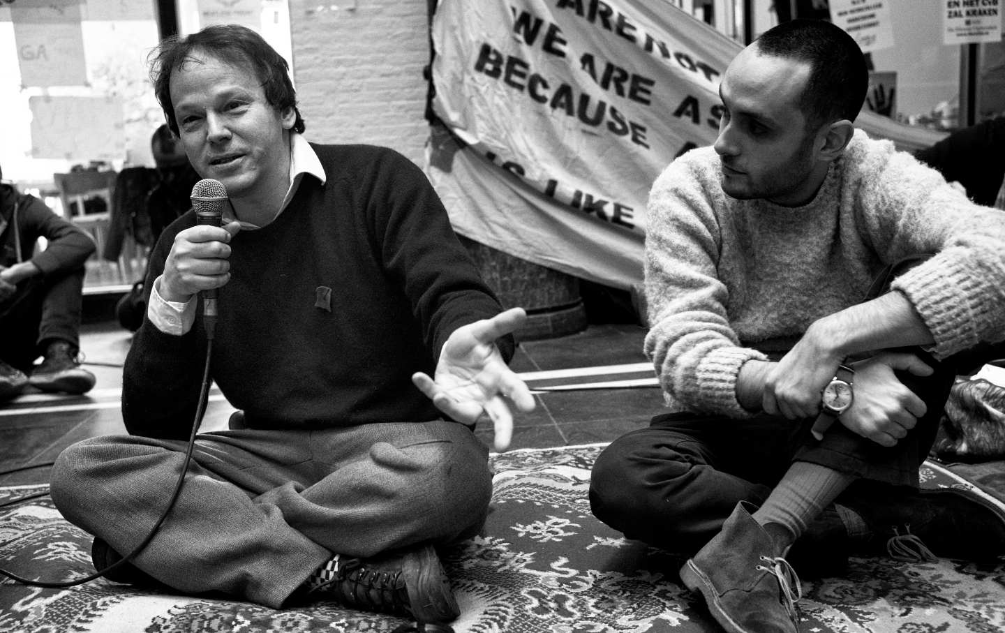 David Graeber holds a microphone and speaks at an occupation