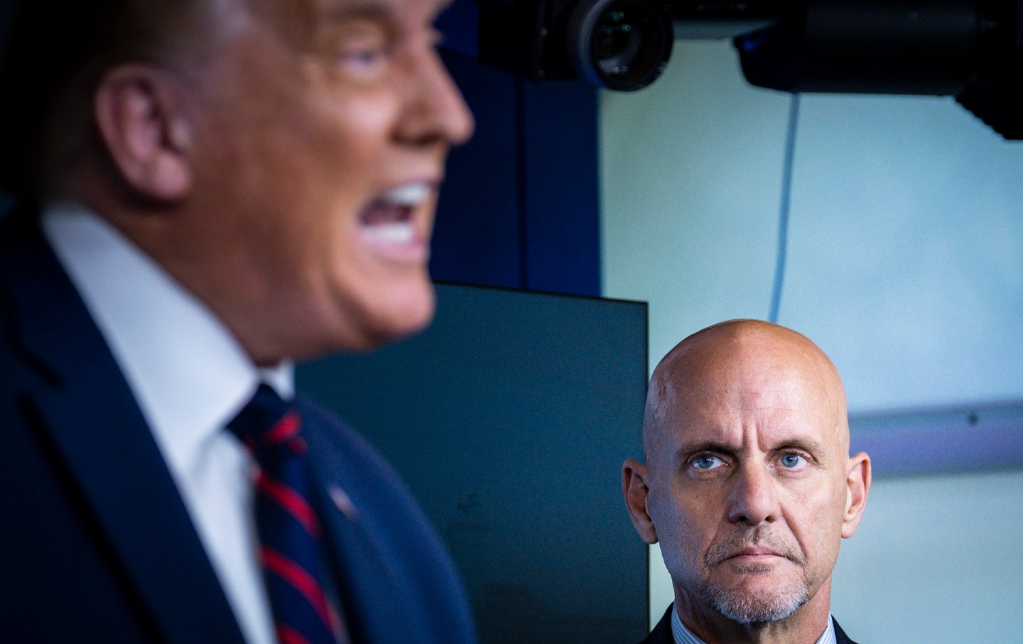 Stephen Hahn watches Donald Trump at a press conference.