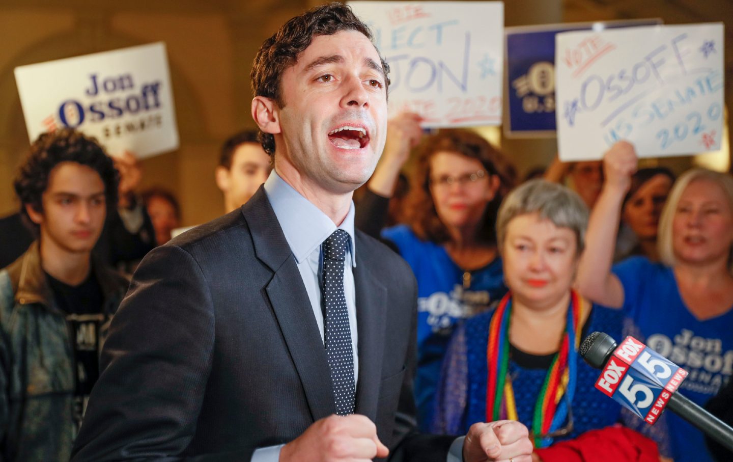 Jon Ossoff speaks to the media, surrounded by a supportive crowd.
