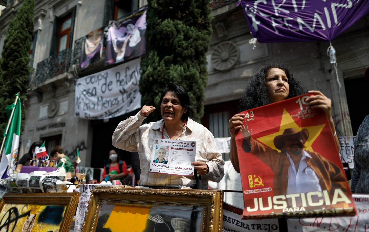 Women stand holding posters and calling for justice.