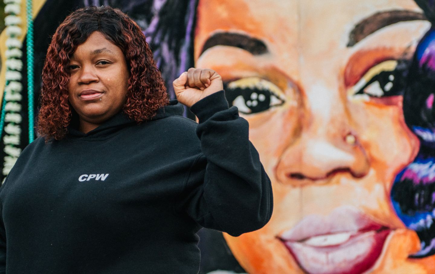 Tamika Palmer holds her first up in front of a mural of Breonna Taylor's face