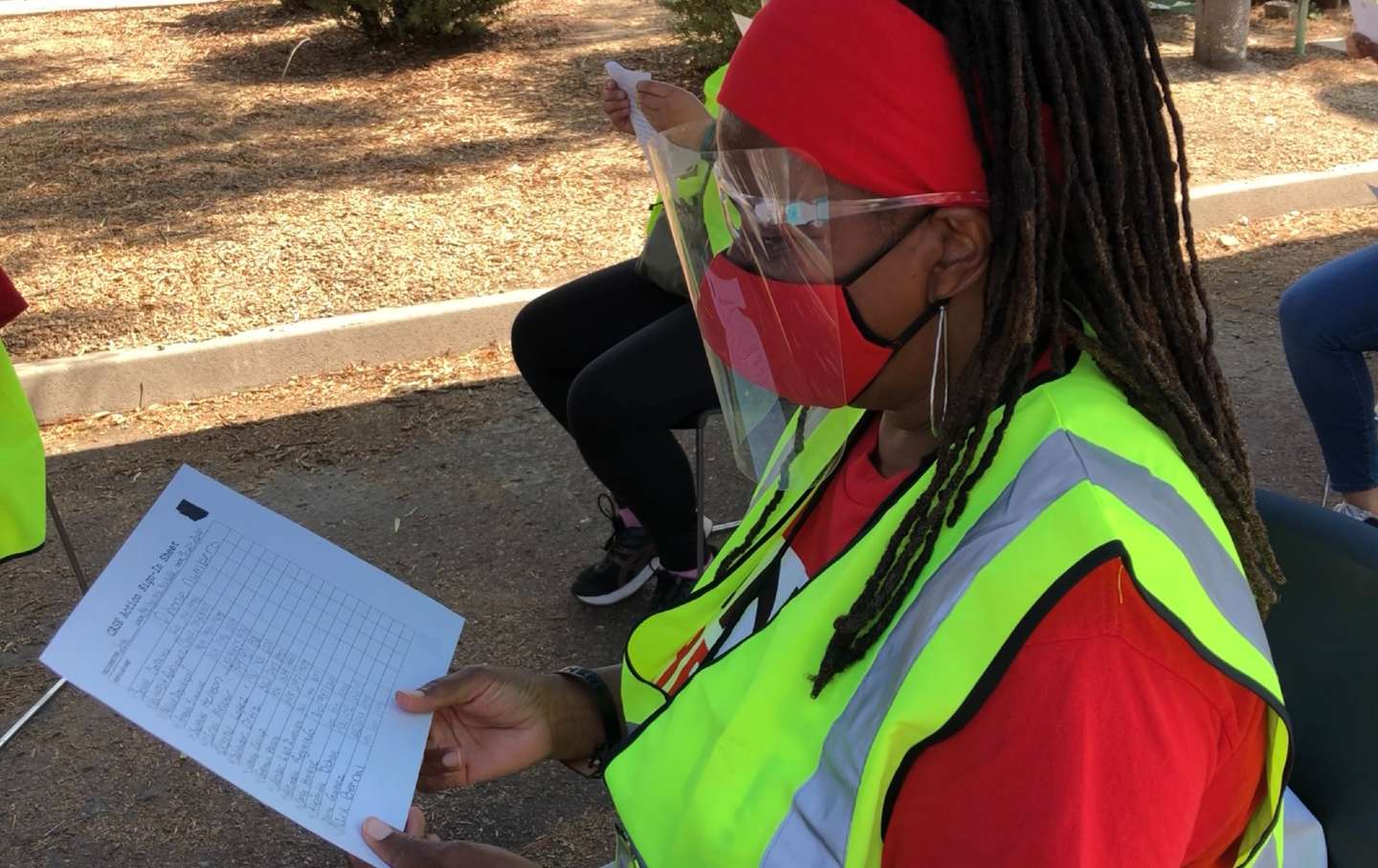 A CASE canvasser in PPE reviews a list of names.