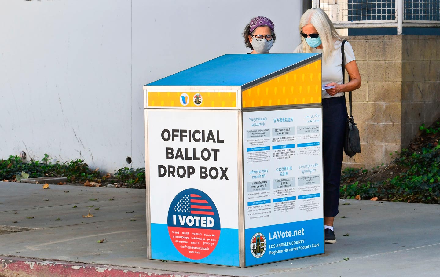 Two women dropping election ballots in drop box 