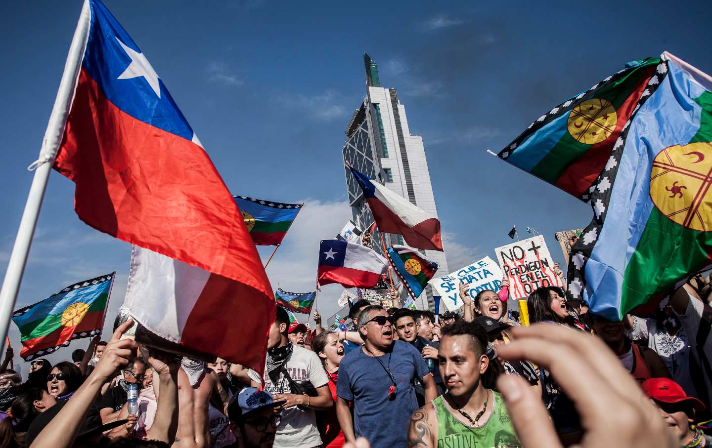 A crowd of protesters, several with Chilean flags