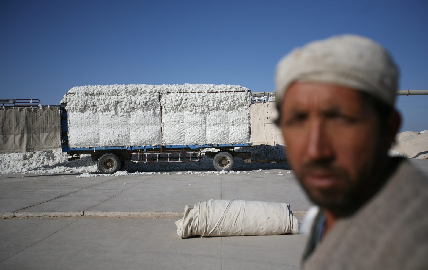 A truck full of cotton is dropped off next to a ginning depot.