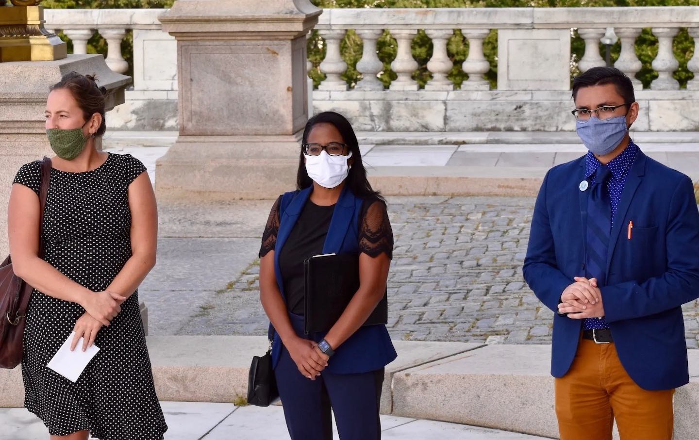 Three members of Reclaim RI speak at an event.