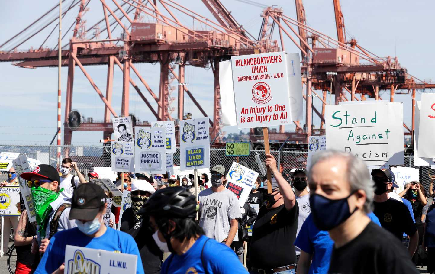 Workers hold signs at a protest with slogans like 