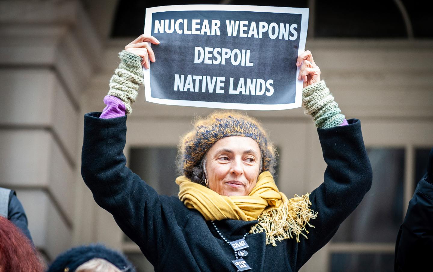 Woman in a knit cap holding a sign that reads 