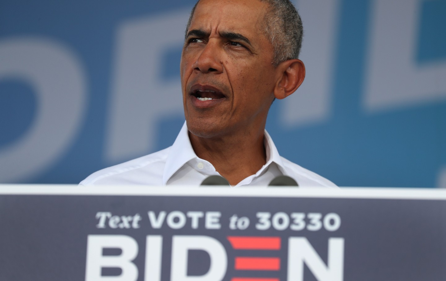 Barack Obama speaks to a crowd in front of a Biden 2020 sign