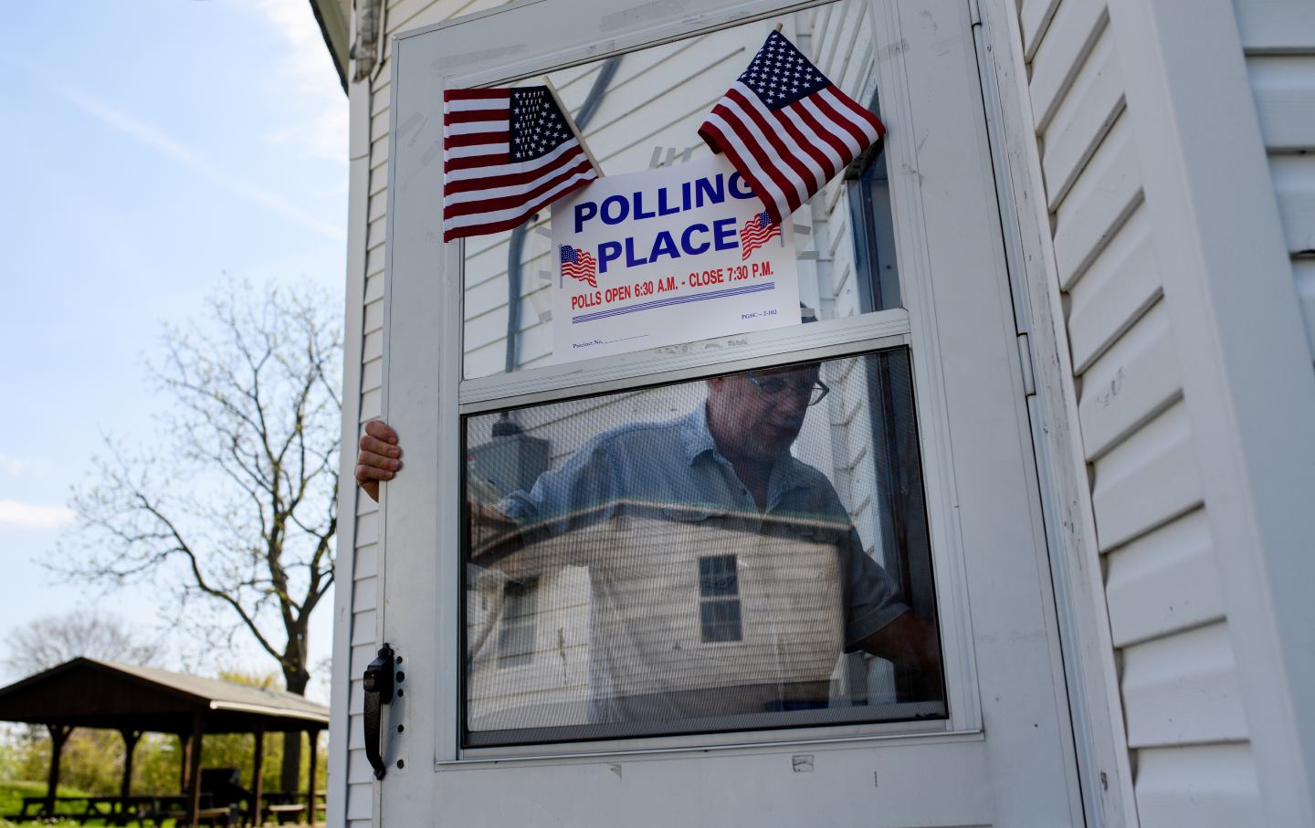 Man walks into polling place marked with American flags.