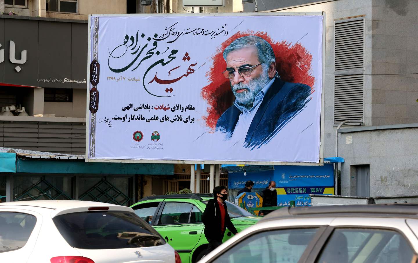 Vehicles drive by a billboard featuring Mohsen Fakhrizadeh