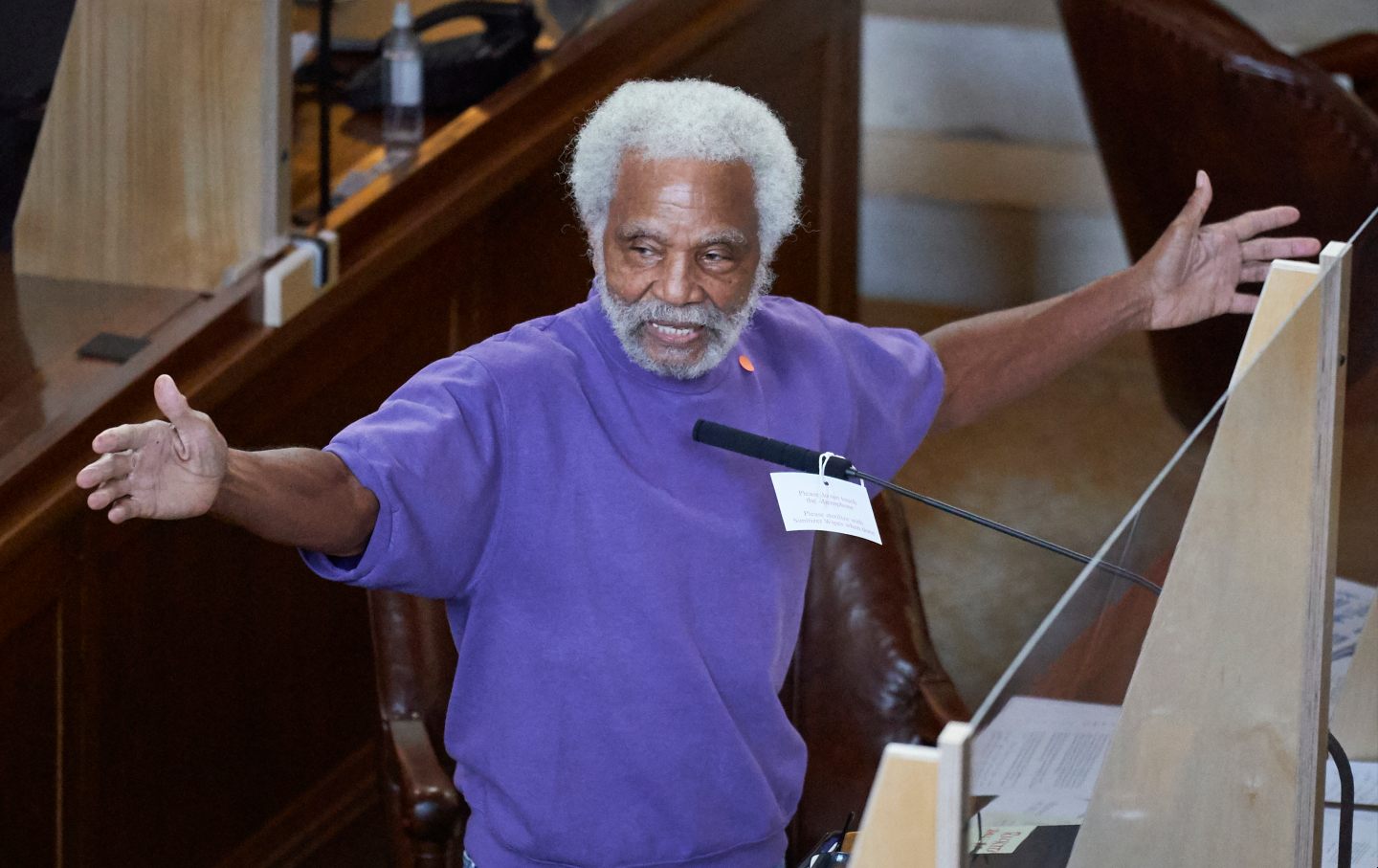Ernie Chambers extends his hands while speaking in front of a microphone