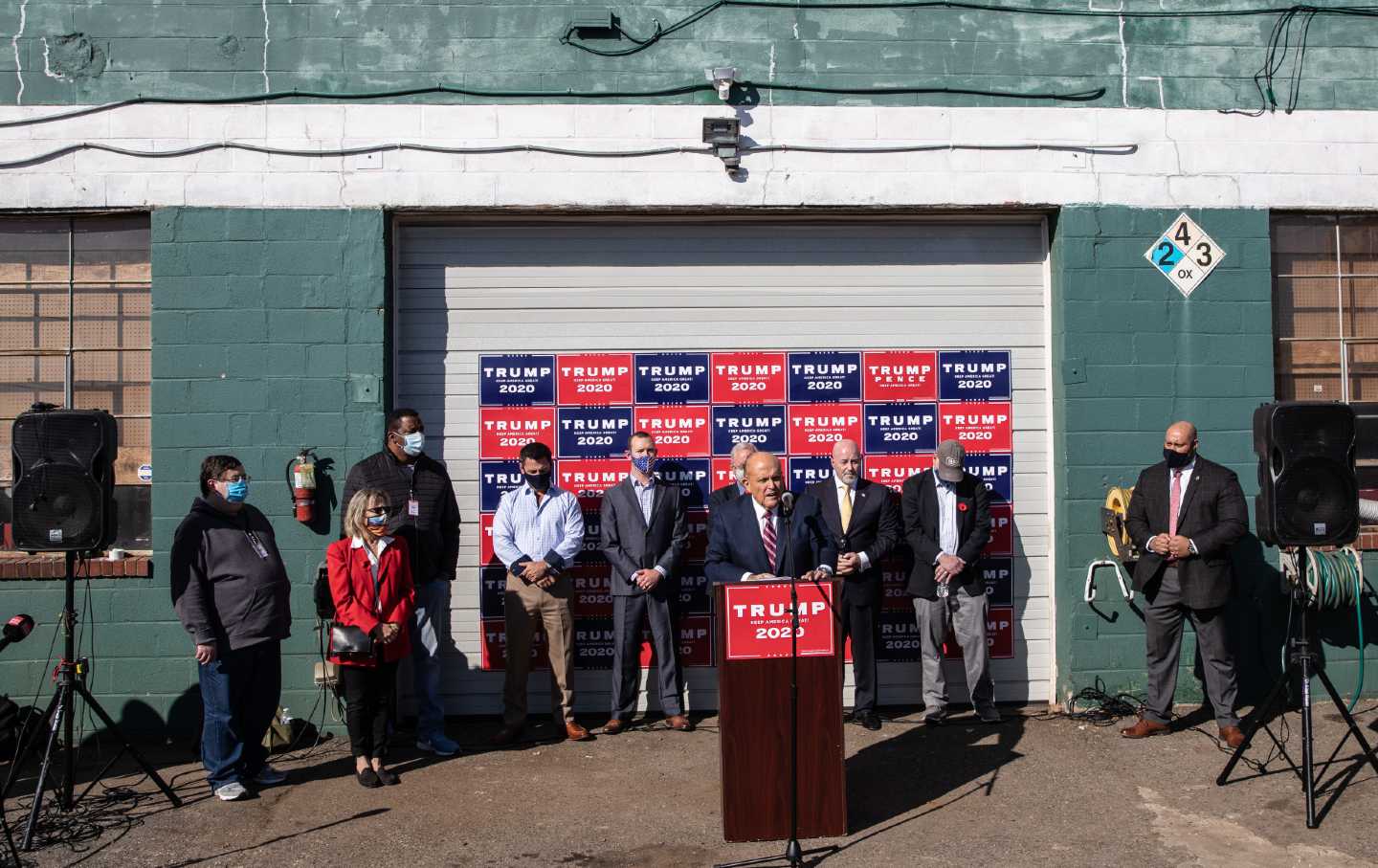 Rudy Giuliani stands at a podium speaking to the press