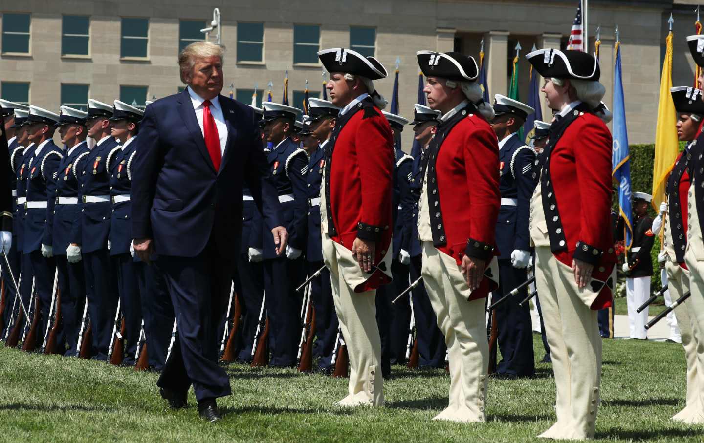 Donald Trump walks past a row of troops in full uniform.