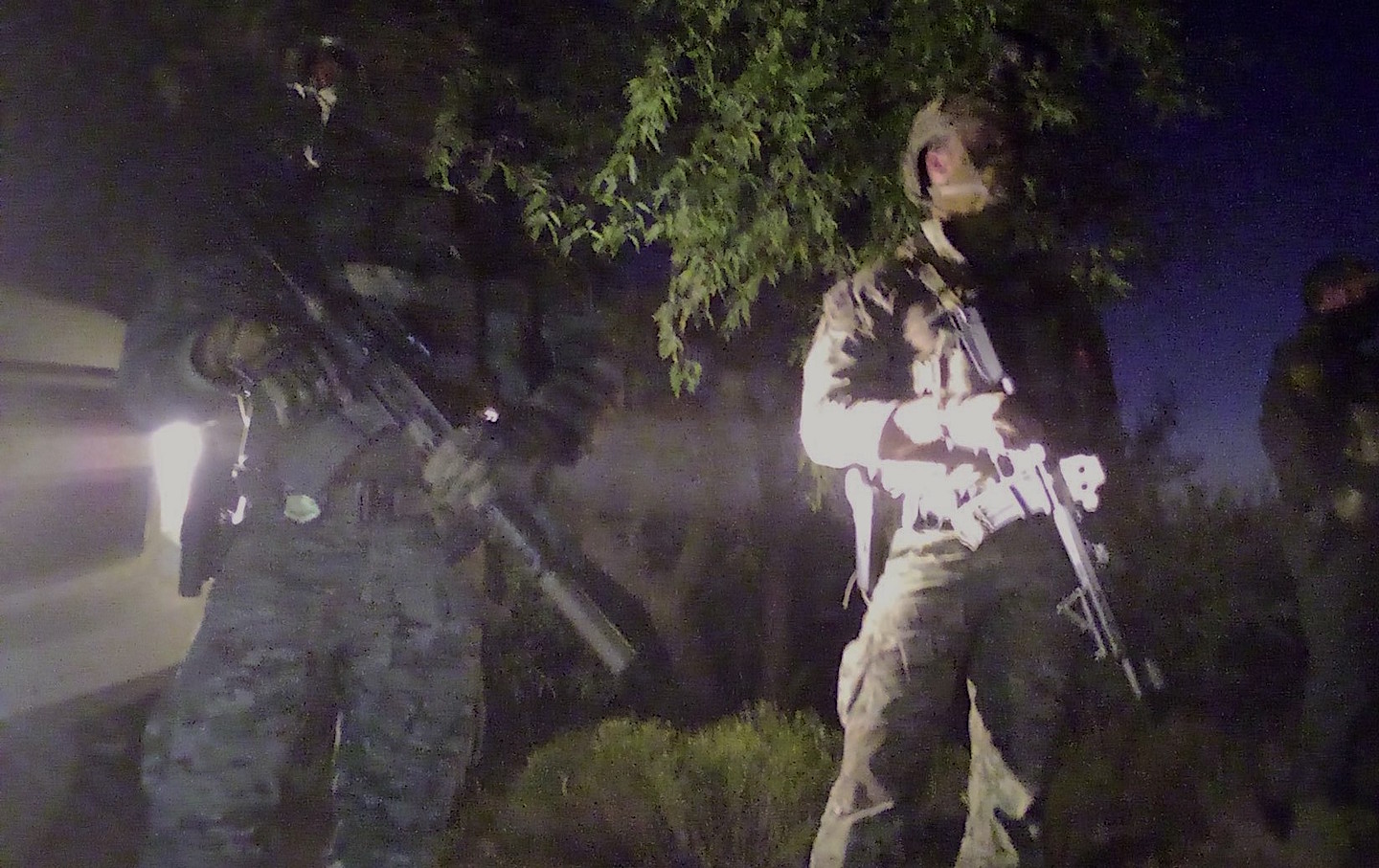 Agents with guns standing in camp