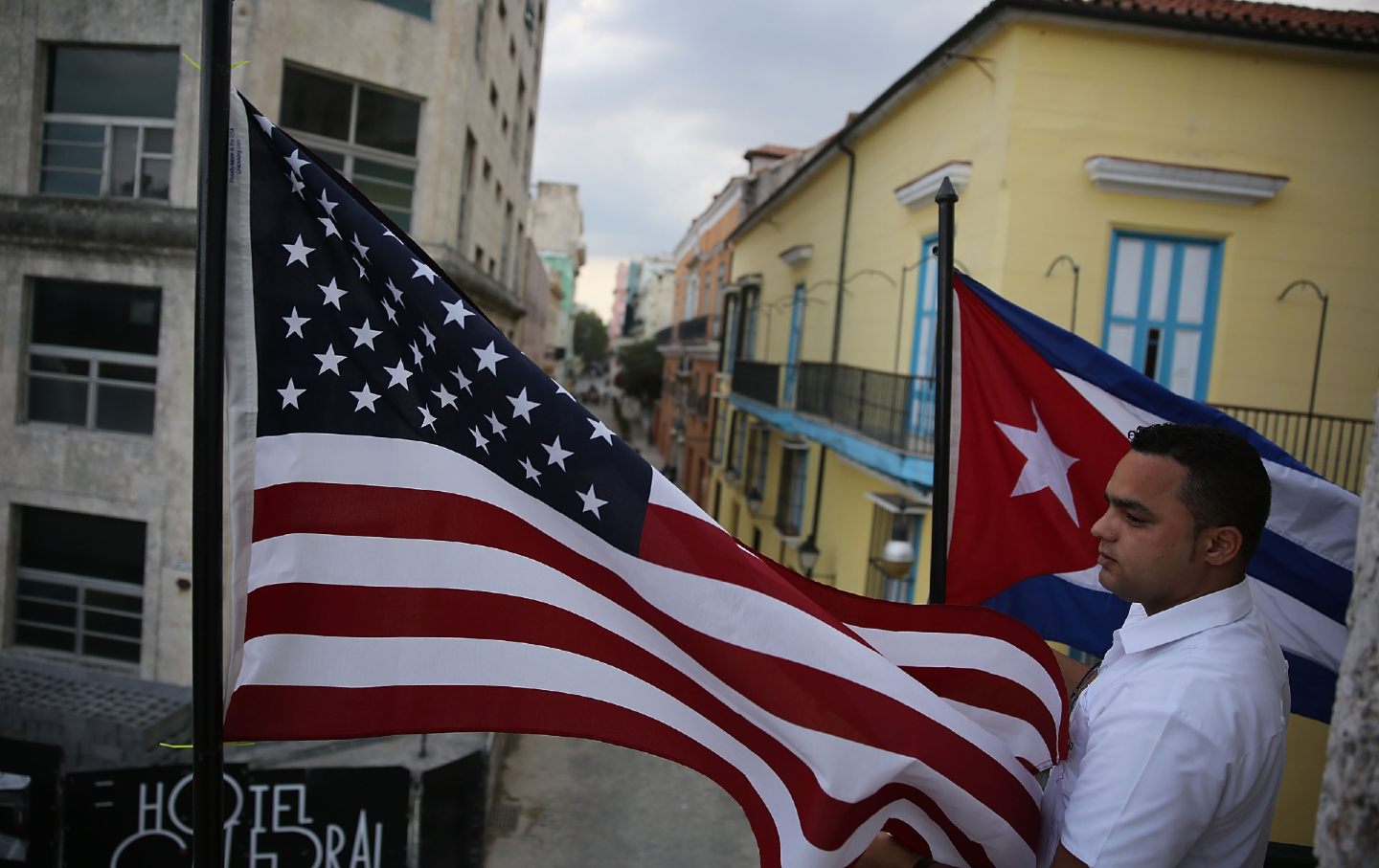 Jose Alfredo stands between an American flag and a Cuban flag