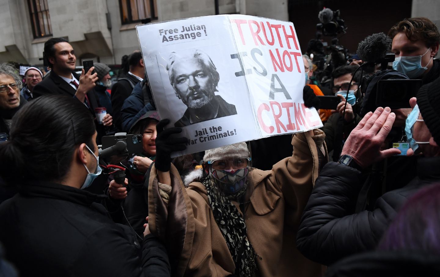 Julian Assange supporters celebrate outside, one holding a sign that says 
