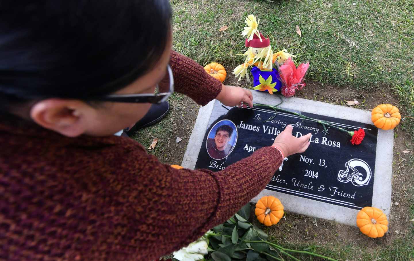 Mother of James De la Rosa places flowers on her son's grave