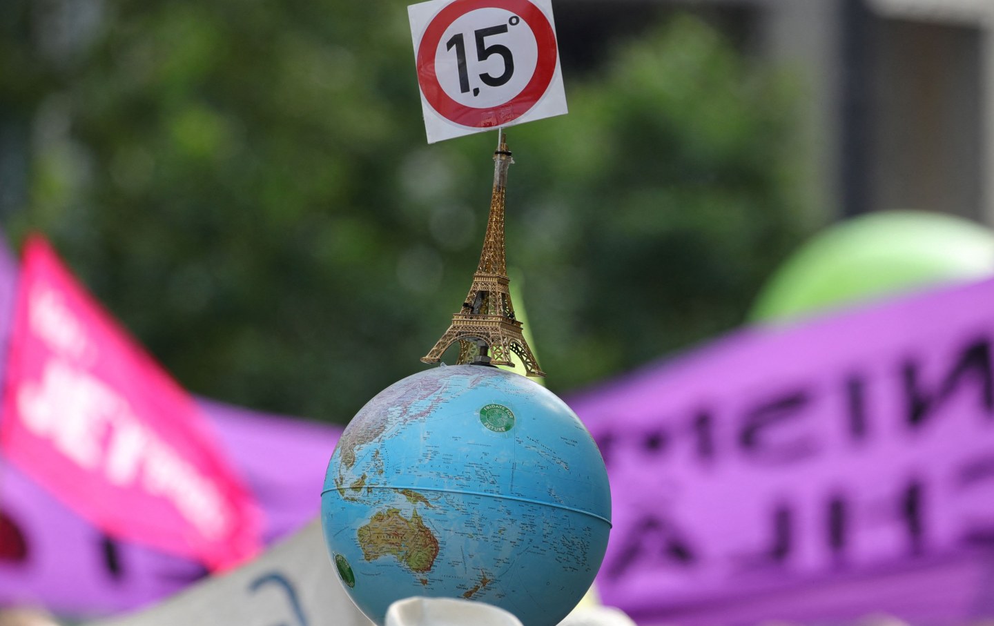 A globe with a mini Eiffel tower on top of it, with a sign of 1,5 degrees Celsius