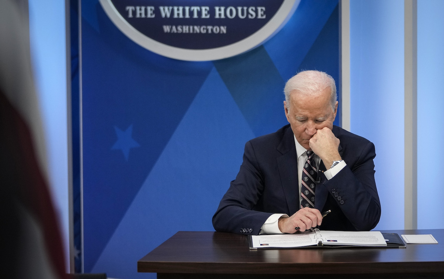 Biden leaning his cheek on his fist.