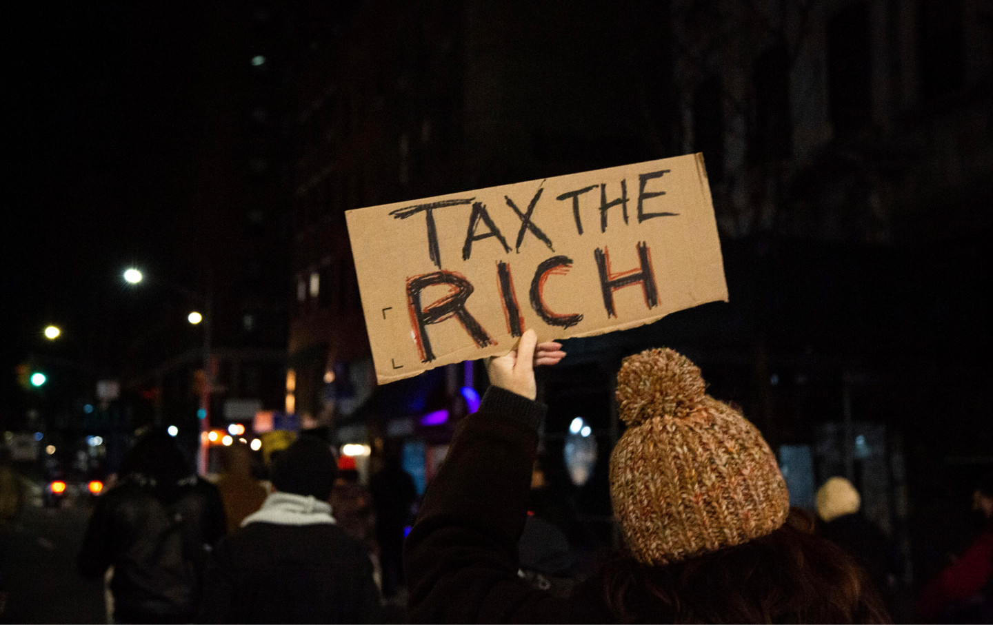 A woman holds a cardboard sign that says 