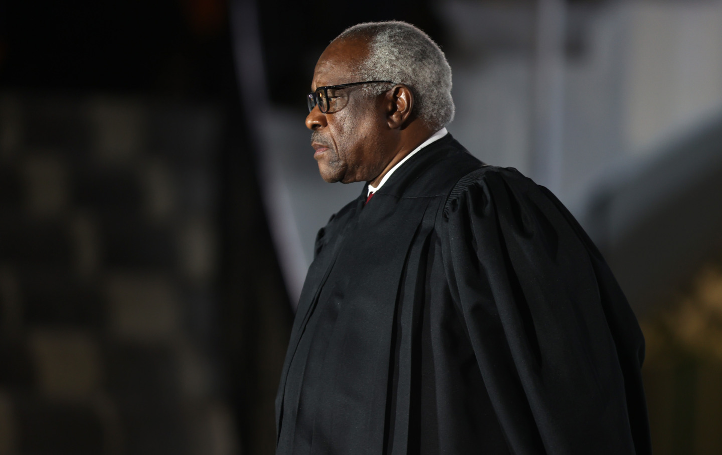 Clarence Thomas looks into the distance in a black judge's robe