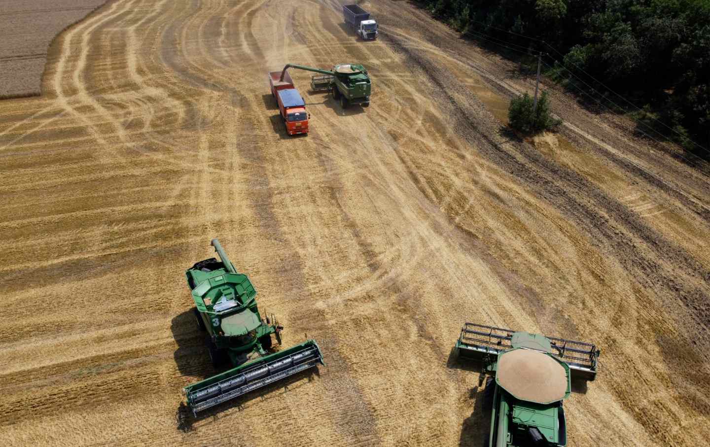Farm equipment seen from above a harvested field.