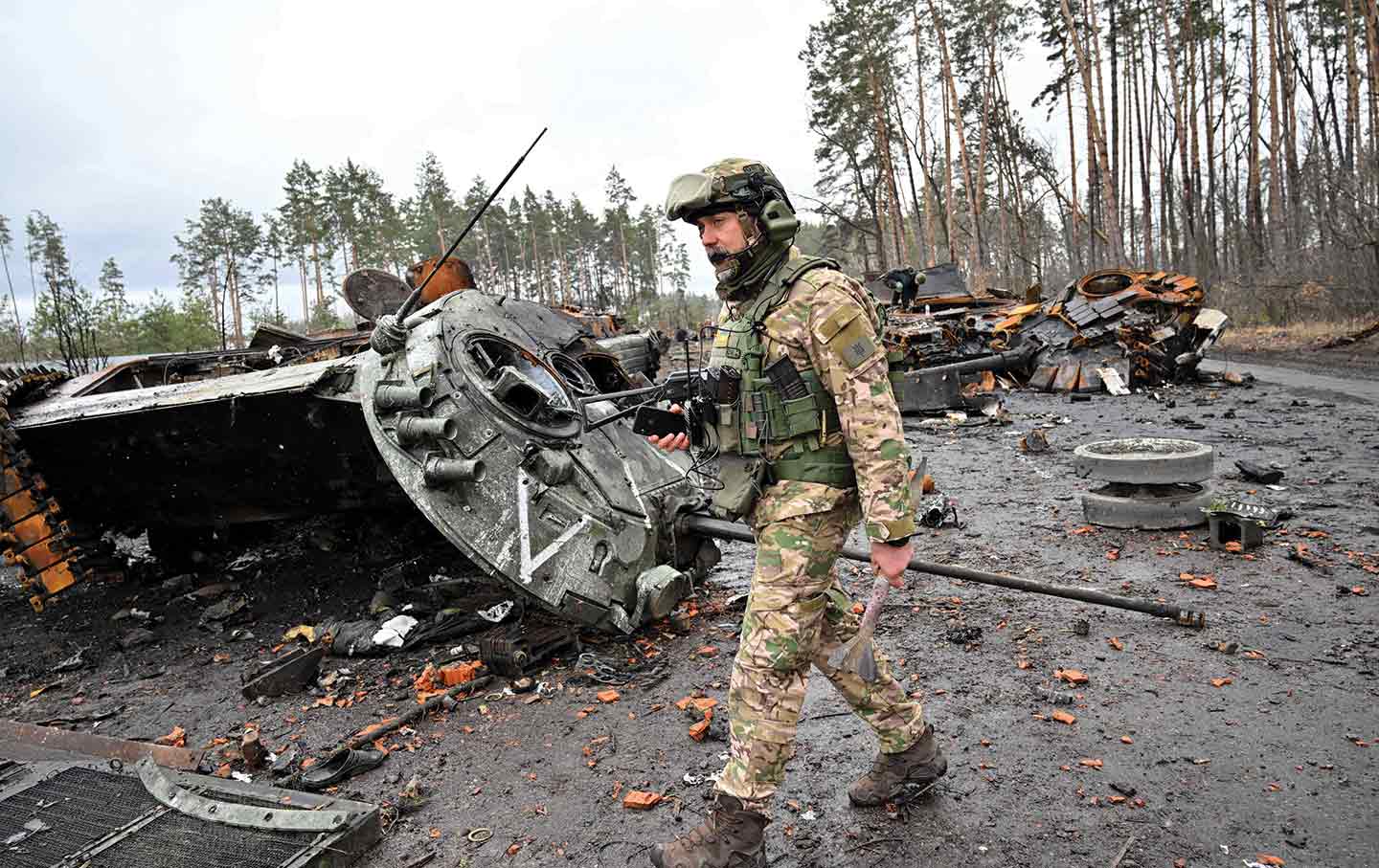 A Ukrainian serviceman walks past destroyed Russian tanks