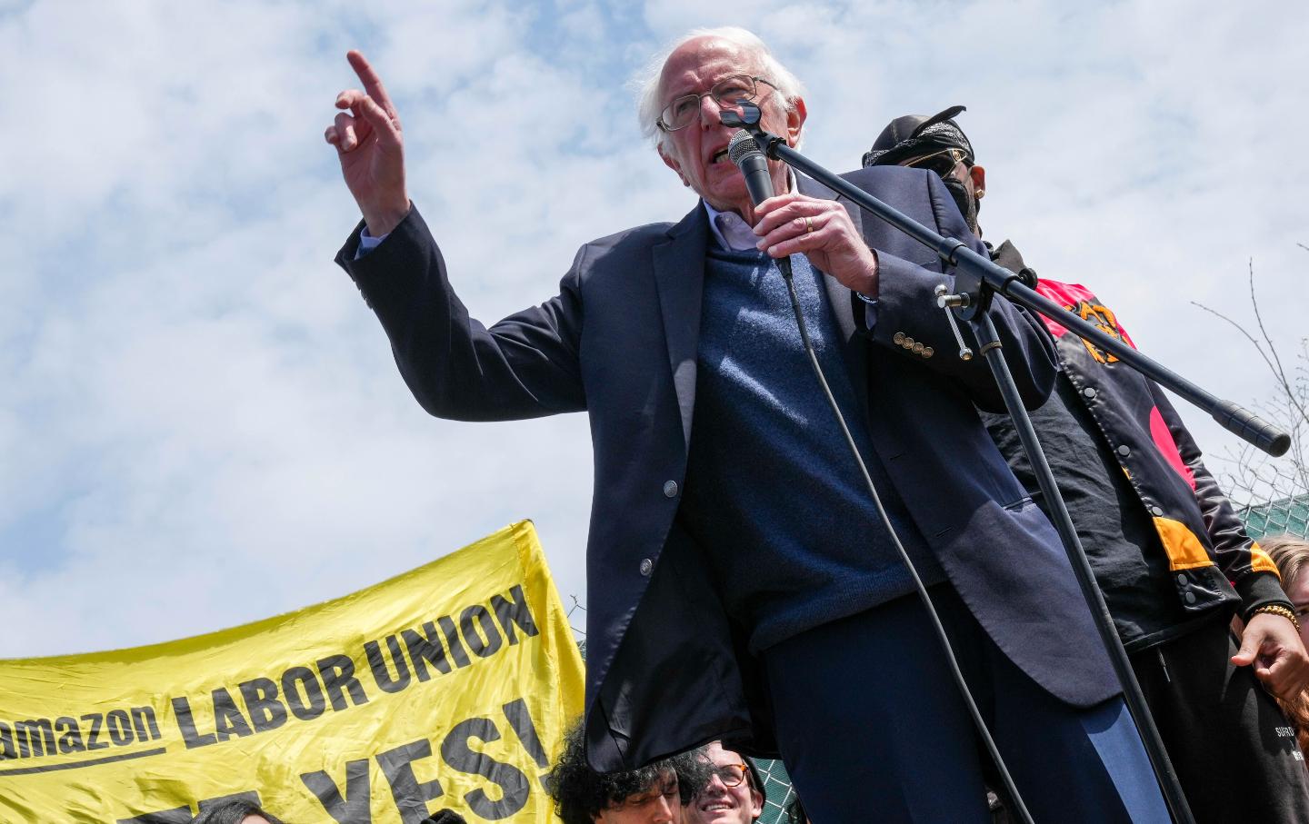 Bernie Sanders points up in the air.