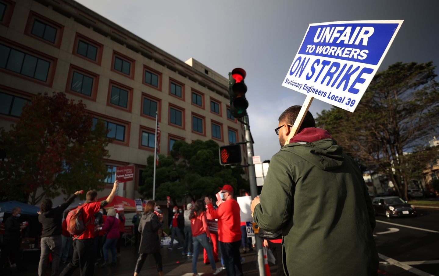 Workers with their backs to the camera wearing red and holding signs