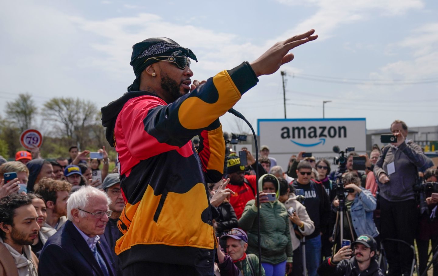 A man holds a microphone surrounded by a crowd.