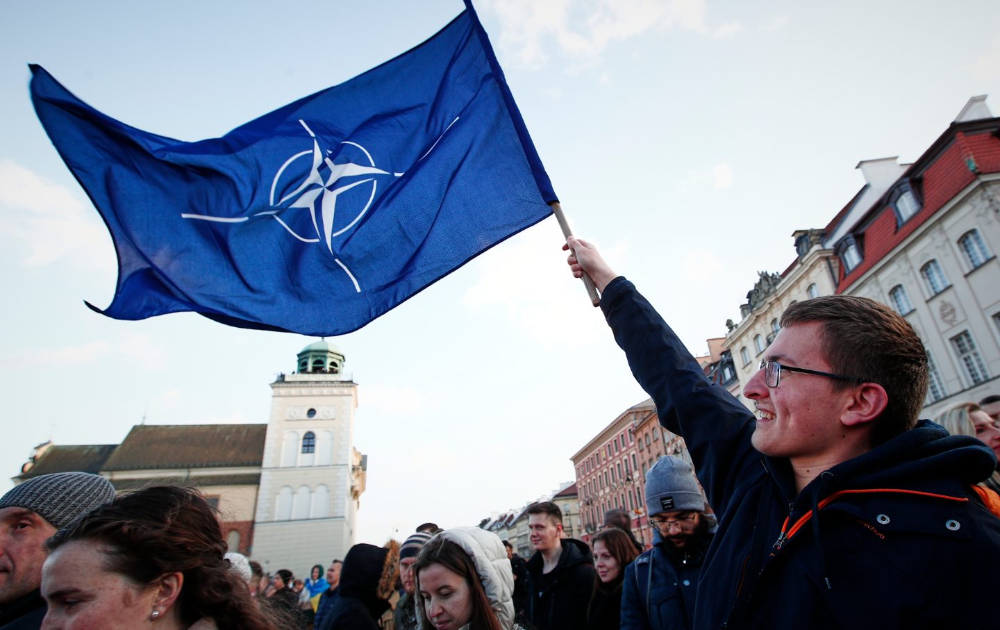 A man waves a blue flag in a crowd