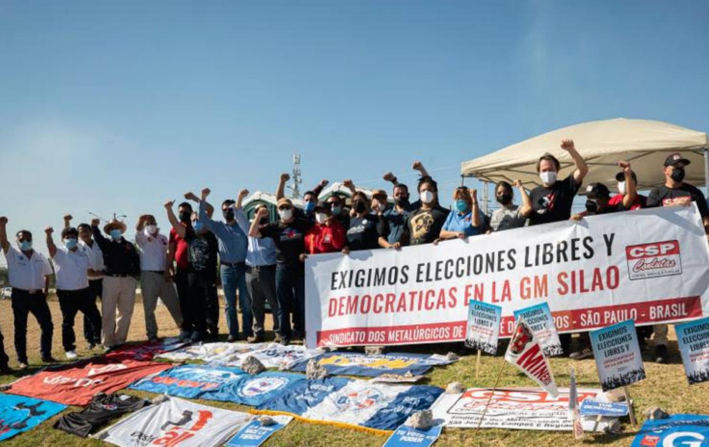 People stand around colorful signs with their fists raised.