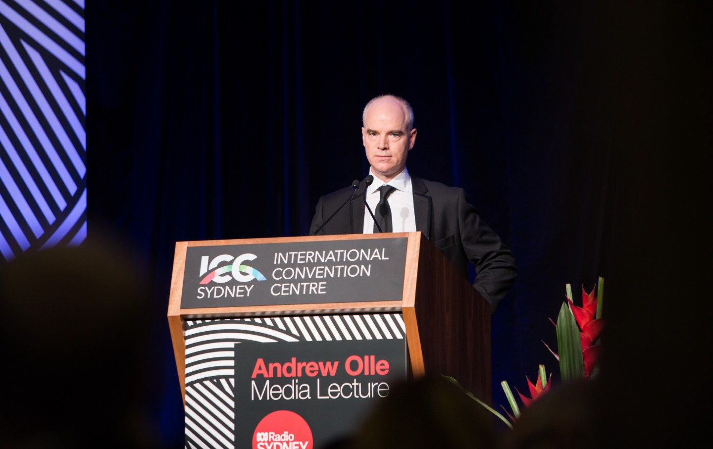 A man in a suit stands at a lectern