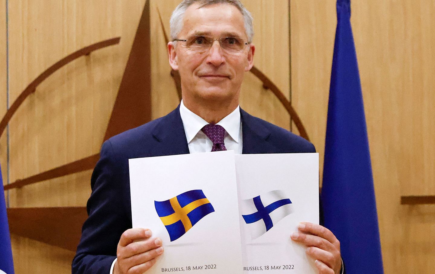 NATO Secretary General holds images of Sweden's and Finland's flags.