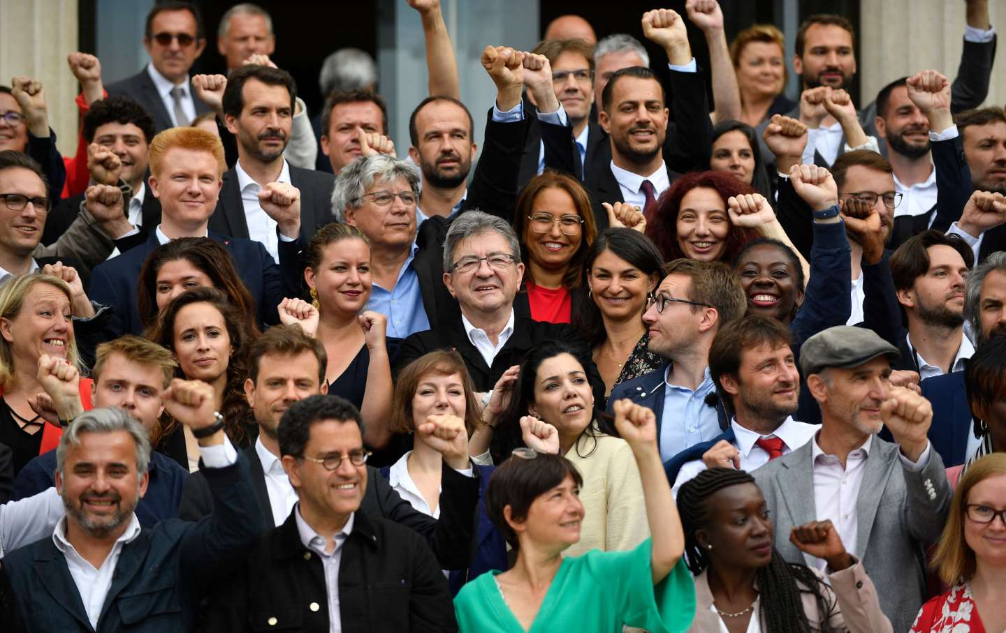 A crow of people in formalwear stands with fists raised.