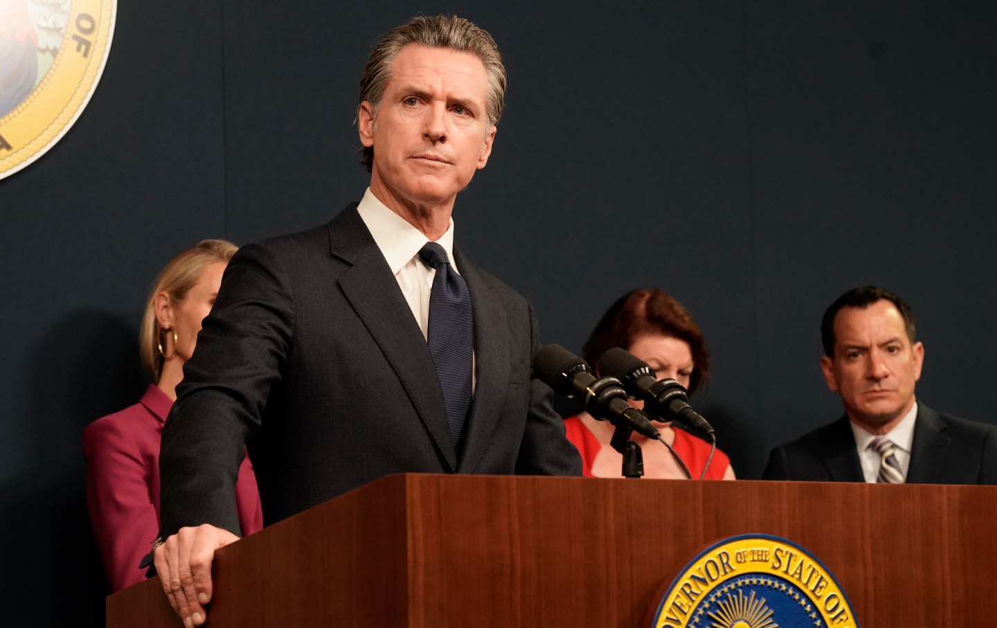 Gavin Newsom looks into the distance from a lectern.