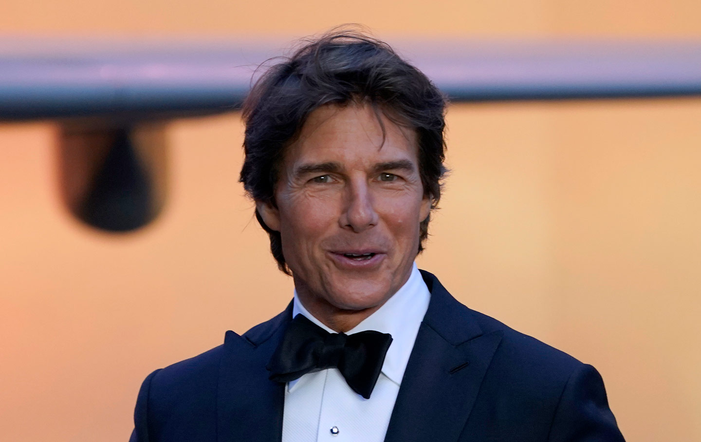 Tom Cruise poses in a navy tuxedo with black bow tie.