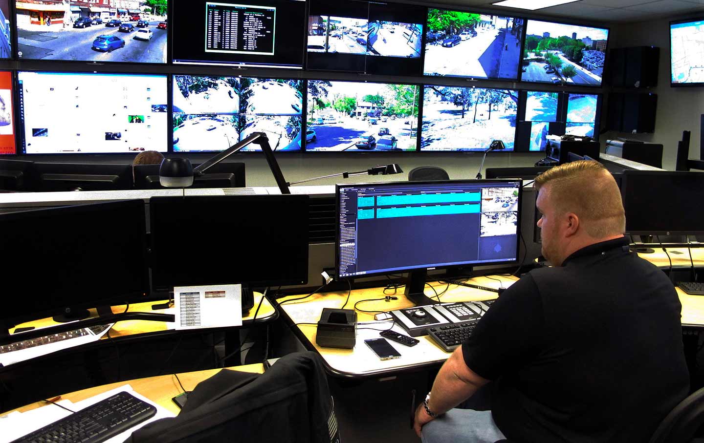 A police looks at a series of row of monitors.